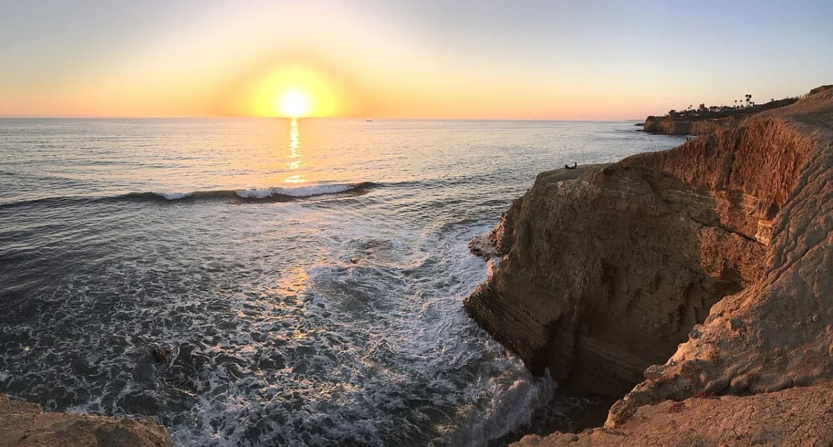 Hikers walking the blufftop trail at Sunset Cliffs with the Pacific Ocean stretching to the horizon